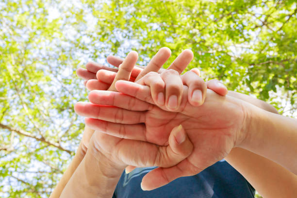 istock young people joining hands together in nature background. Concept unity and teamwork 973655634