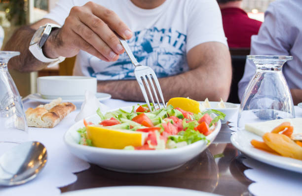 istock Young man eating salad at a restaurant 973658260