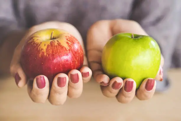 Photo of woman hand holding red and green apple fruit for dieting concept background