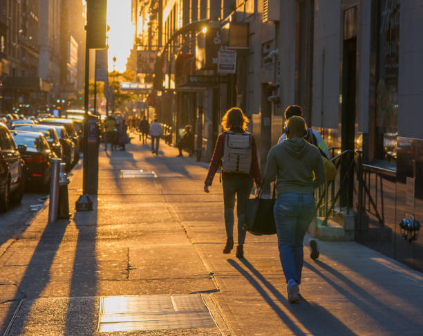 People walking on 35th Street side walk towards the setting sun on a cool early summer day stock photo