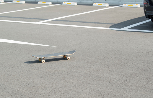 A skateboard is rolling in the parking lot.