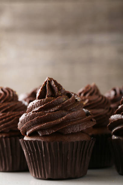 istock Tasty chocolate cupcakes on wooden table 973685536