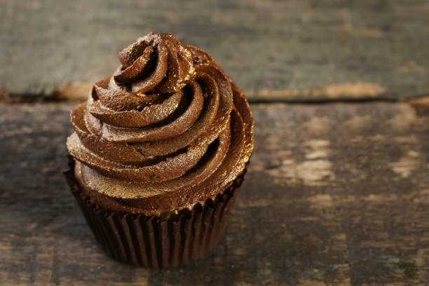 istock Chocolate cupcake on wooden table 973686112