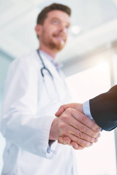 istock Inspired doctor shaking hands with a businessman 973701228