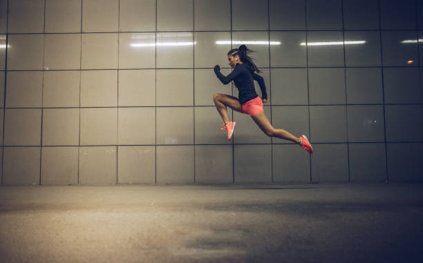 Skilled girl One woman, young and fit woman, training outdoors at night alone, long jump training. long jump stock pictures, royalty-free photos & images