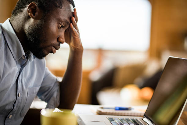 istock Worried African American man using laptop at home. 973704526