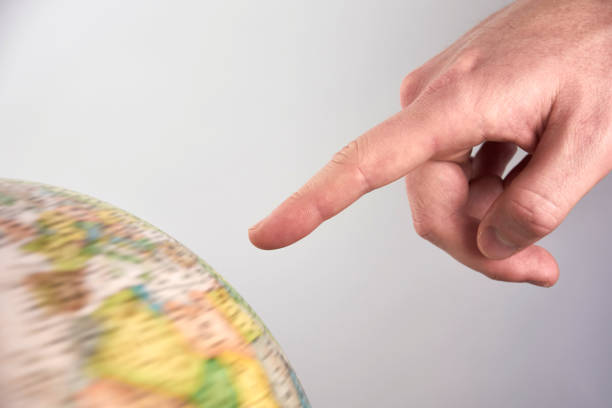 istock Young man's hand pointing to a rotating globe - on a white background 973705218