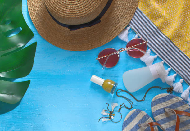 istock Summer holidays female accessories flat lay with hat, monstera leaf, sunglasses, flip flops, necklace, cream, nail polish and beach towel 973708232