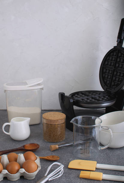 istock Cooking background of waffle preparation with batter, waffle iron, kitchen utensils and ingredients 973708254