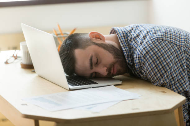 istock Tired male worker sleeping at laptop at office desk 973708850