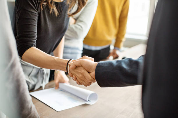 Business people shaking hands in office Cropped shot of businessman greeting a young professional around the table in office. Close up of business people shaking hands in office. partnership stock pictures, royalty-free photos & images