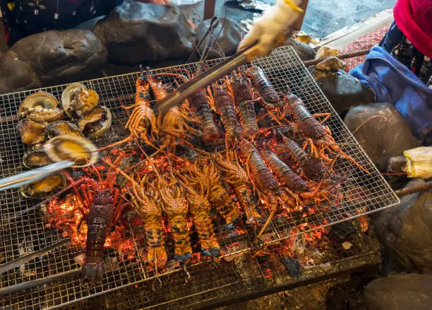 Photo of Fresh Abalones and Japanese spiny lobsters being charcoal grilled in traditional Japanese style in Mie , Japan