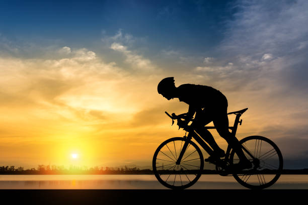 silueta de ciclista en el fondo de la hermosa puesta de sol - andar en bicicleta fotografías e imágenes de stock