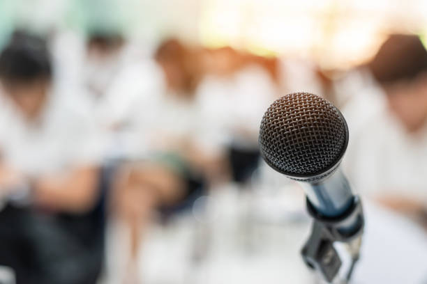 istock Microphone voice speaker with audiences or students in seminar classroom, lecture hall or conference meeting in educational business event for host, teacher, or coaching mentor 973722626