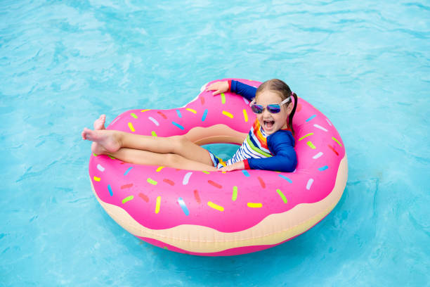 istock Child in swimming pool on donut float 973725564