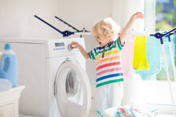 istock Child in laundry room with washing machine 973726026