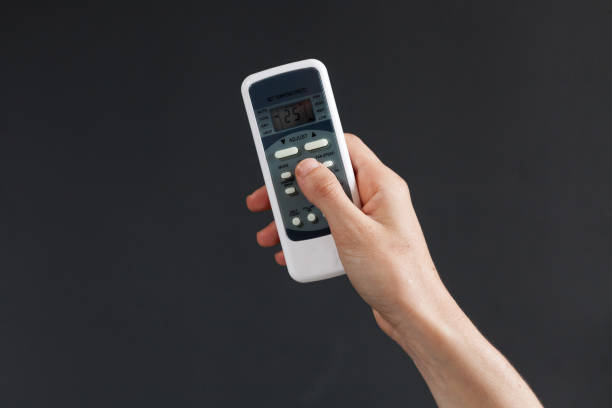 istock Hand using a remote control to activating air conditioning on the dark background 973726844