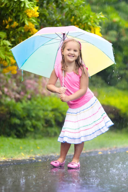 istock Kid with umbrella playing in summer rain. 973726898
