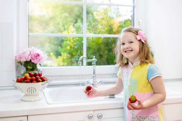 白いキッチンにイチゴを洗う少女 - washing fruit preparing food strawberry ストックフォトと画像
