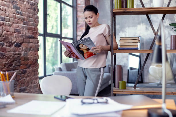 istock Focused female employee reading magazine 973736096