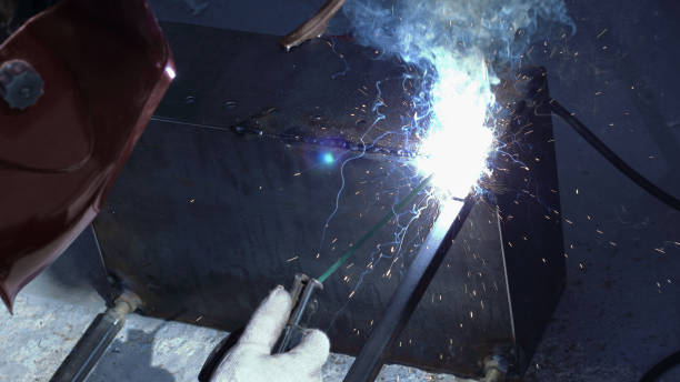 istock welder processes the part, workplace, sparks and flames fly in different directions 973740026