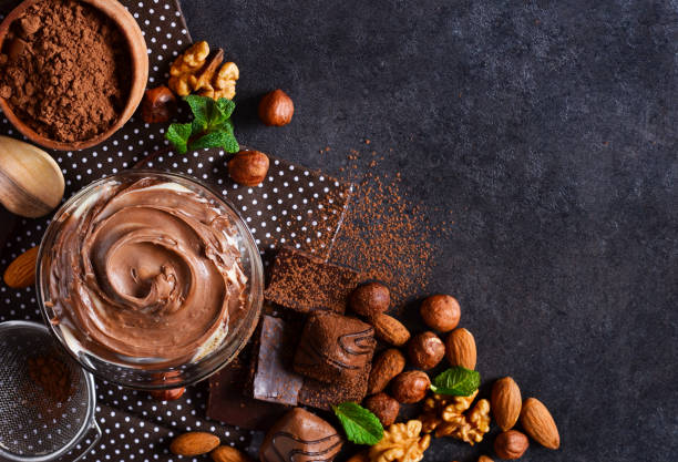 istock Black food background with cocoa, nuts and chocolate paste. top view 973740784