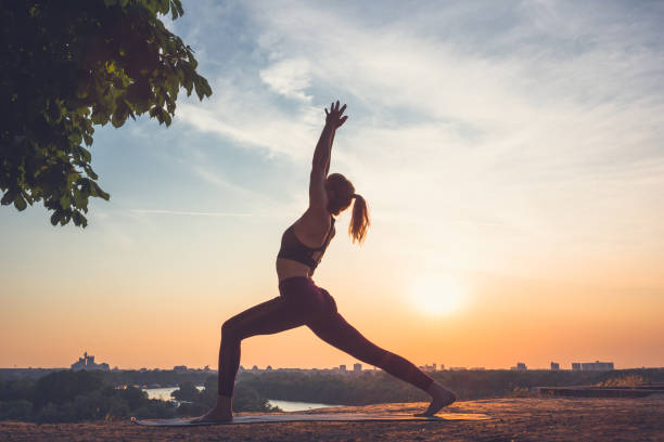 istock Woman practising yoga outdoors. Summer sunset 973745906