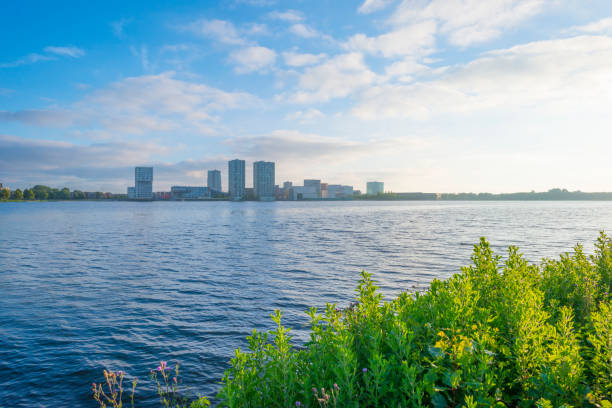 skyline de una ciudad a lo largo de la orilla de un lago al amanecer en primavera - almere fotografías e imágenes de stock