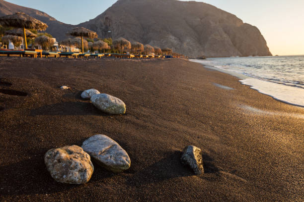 perissa strand bei sonnenaufgang auf der griechischen insel santorini - black sand beach santorini greece stock-fotos und bilder