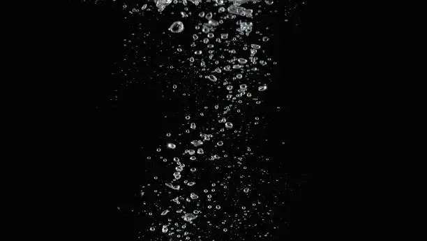 Photo of Soda water bubbles splashing and floating drop in black background