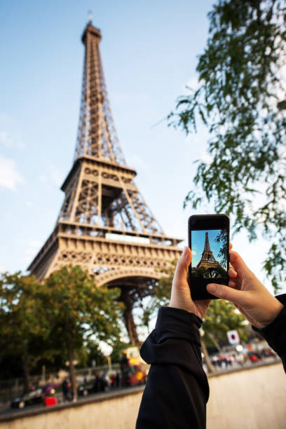 tourist nimmt bild mit handy des eiffelturms in paris, frankreich - clear sky low angle view eiffel tower paris france stock-fotos und bilder