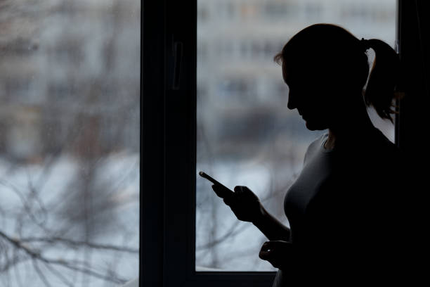 istock woman using smart phone at window house background 973770990