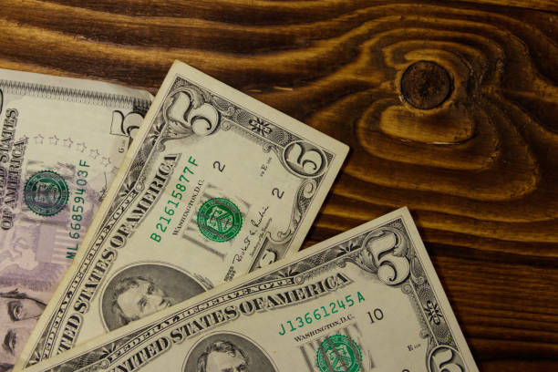 istock Five dollars banknotes on wooden background. Top view 973780300