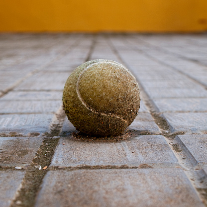 Old and dirty tennis ball in floor with low angle