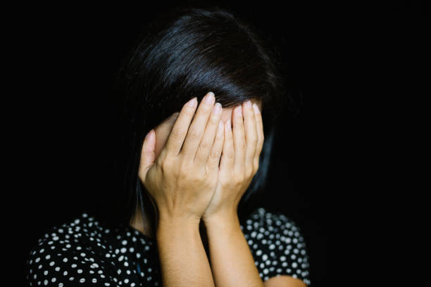 istock Woman Covering Her Face On Black Background 973786768