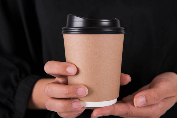 istock Hand holding coffee paper cup. mock up for creative design branding. 973801644
