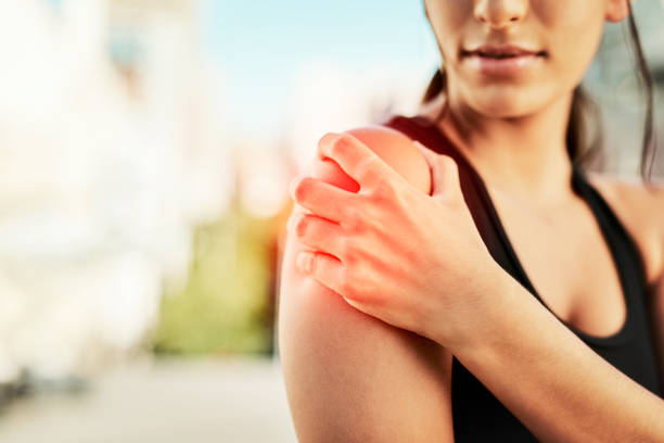 I need some urgent treatment for this Closeup shot of a sporty young woman holding her shoulder in pain while exercising outdoors shoulder stock pictures, royalty-free photos & images