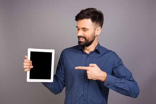 Happy young man pointing on black screen of tablet