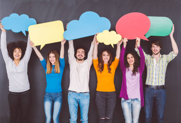 istock Friends holding speech bubbles against blackboard 973840588