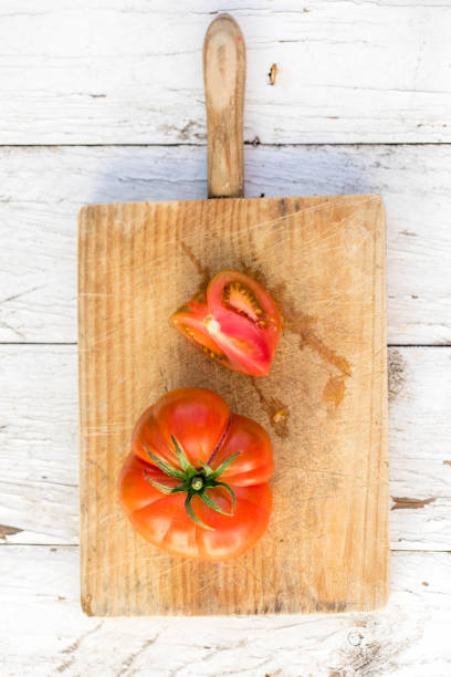 istock Ripe  tomatoes  on cutting board on  old wooden table, copyspace. Beefsteak tomatoes kind for cooking. Food organic concept