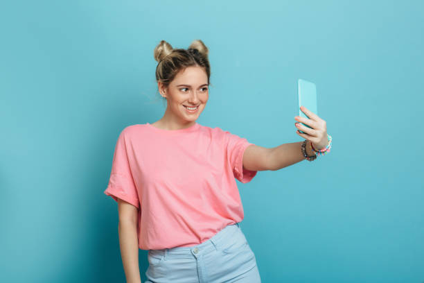 mujer haciendo fotos en su smartphone sobre fondo azul - montar fotos fotografías e imágenes de stock