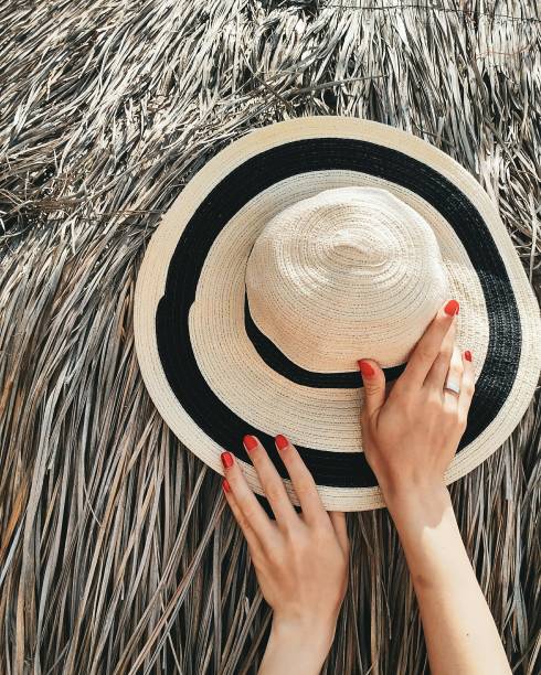 Summer hat with hands. Manicure red nails flat lay.