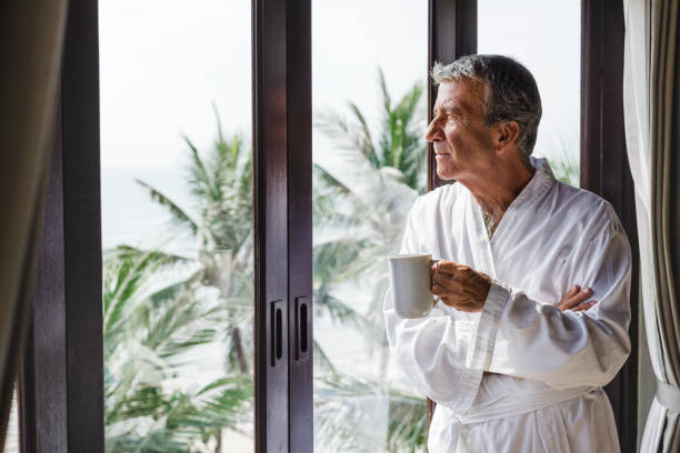 istock Mature man looking out the hotel window 973894844