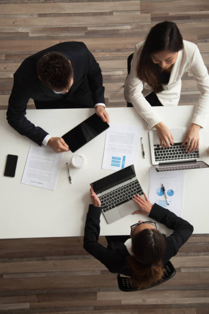 istock Colleagues working together at meeting using devices, top vertical view 973912954