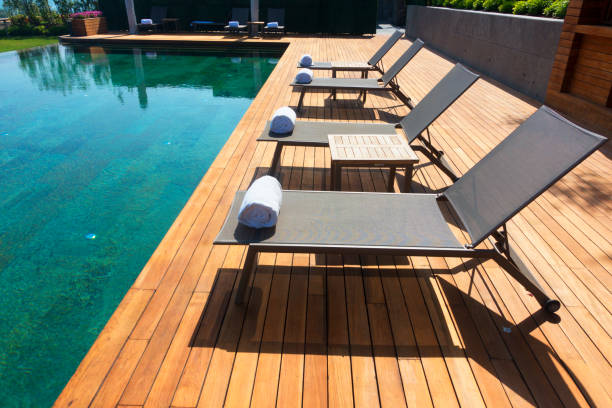 istock Deck chairs on Wooden plank floor against swimming pool 973920648