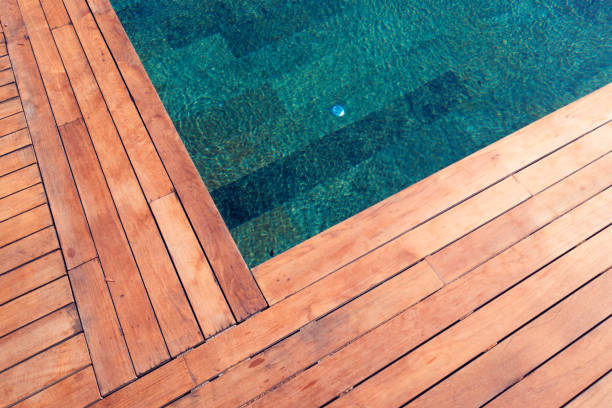 istock Wooden plank floor against swimming pool 973922948