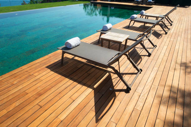 istock Deck chairs on Wooden plank floor against swimming pool 973923210