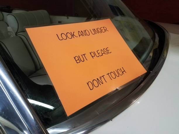 istock look and linger but please don't touch sign on automobile window 973925884