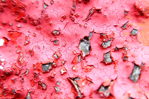 Macro light blurry photo of painted wall with red cracked color surface. Selected focus.