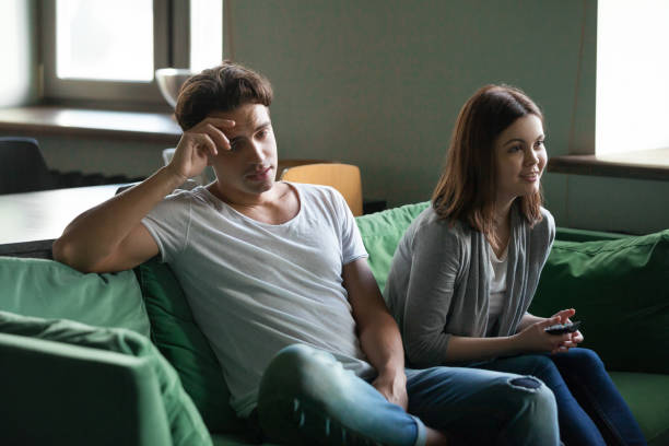 istock Disinterested boyfriend getting bored while excited girlfriend watching tv series 973961974